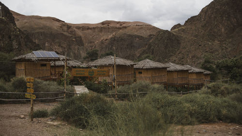 Built structure on land by mountains against sky