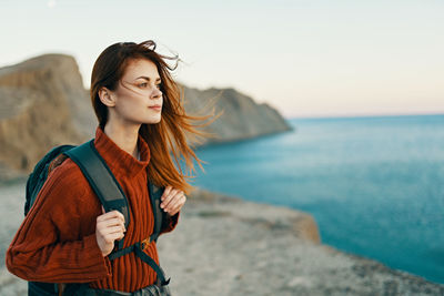 Young woman looking at sea shore against sky