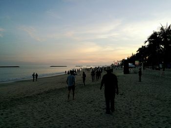 People at beach against sky during sunset