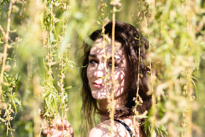 Close-up portrait of young woman amidst plants
