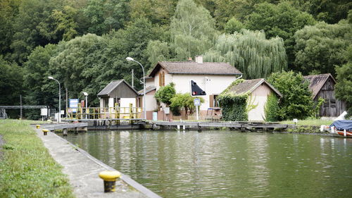 Houses by lake and buildings against trees