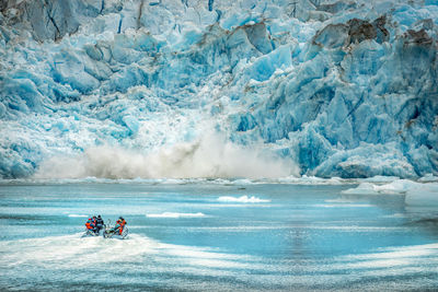 People in boat on river against frozen mountain