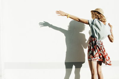 Rear view of woman standing with shadow on white wall