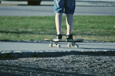 Low section of man skateboarding on road