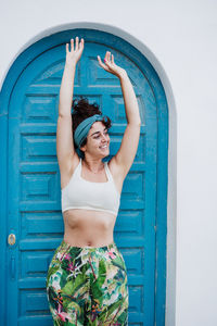 Portrait of woman standing against blue door