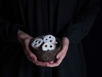 Close-up of cropped hand holding cookies against black background