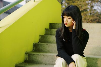 Woman looking away while sitting on staircase