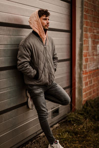 Side view of young man standing against wall