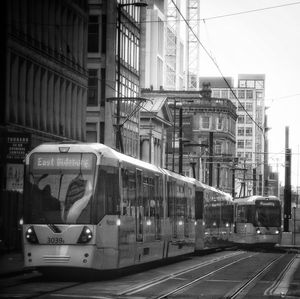 Tram moving on street against buildings in city