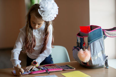 Cute girl packing bag on table at home