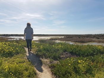 Rear view of woman walking on footpath against sky