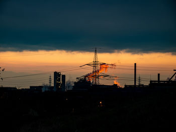 Silhouette of factory against sky during sunset