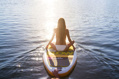 Rear view of woman sitting in sea