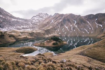 Scenic view of lake by mountains against sky