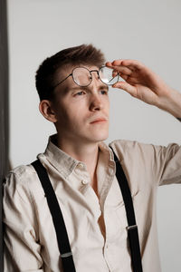 Young man looking away while standing against white background