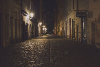 Walkway amidst illuminated buildings at night