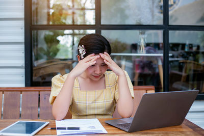 Young woman using mobile phone while sitting on table