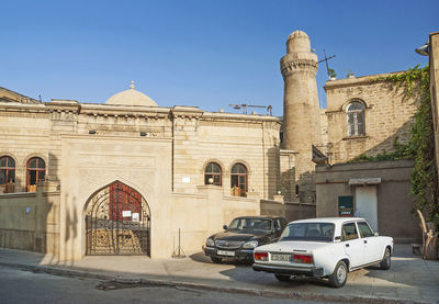 Cars on old building against clear sky