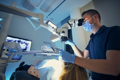 Dentist wearing mask examining girl at clinic