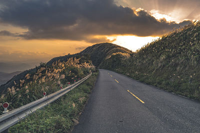 Road by mountain against sky during sunset