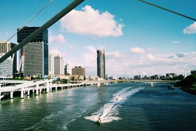 High angle view of boat moving on river by city against sky