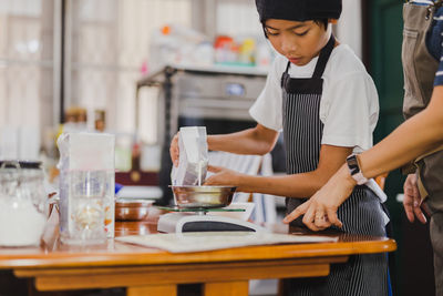 Young boy measuring ingredient for baking in kitchen