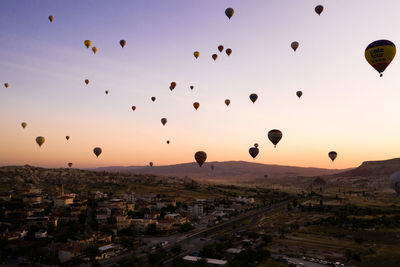 Hot air balloons flying over landscape against sky during sunset