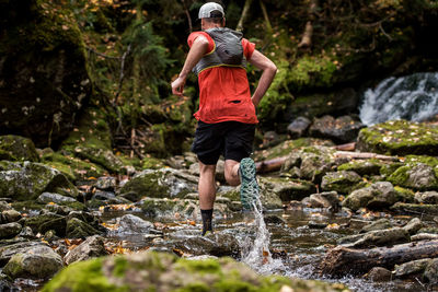 Full length of man standing by rocks in forest