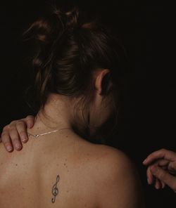 Rear view of shirtless woman against black background