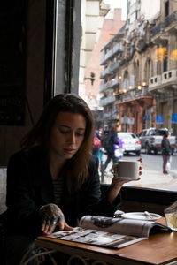 Portrait of young woman drinking coffee while sitting at restaurant
