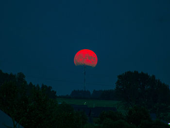 Low angle view of red and trees against sky at night