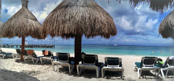 Panoramic view of lounge chairs on beach against sky