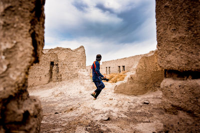 Full length of man standing by old ruin against sky