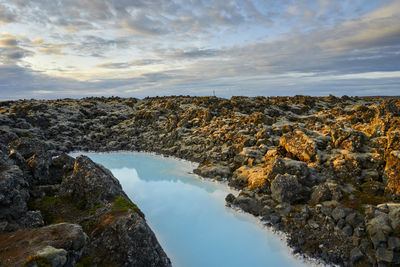 Picturesque landscape of geothermal spring in rocky terrain at sunset