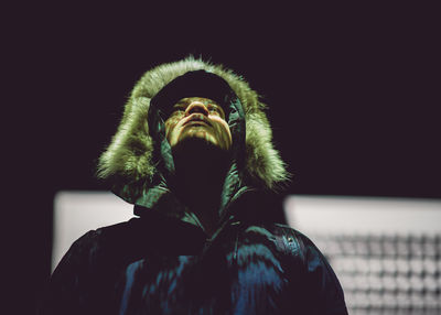 Man in fur coat looking up against wall