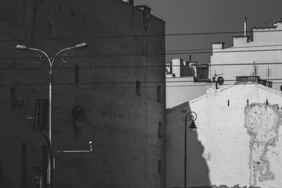 Street light on wall by building against sky