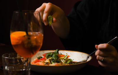 Midsection of woman holding drink on table