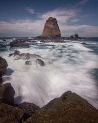 Scenic view of rocks in sea against sky