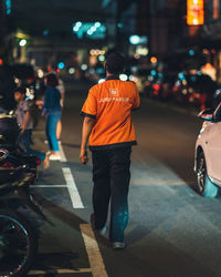 Rear view of man walking on street at night