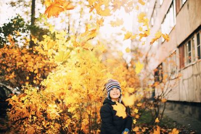 Portrait of boy standing on leaves during autumn