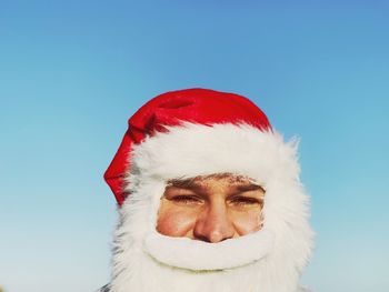 Portrait of senior man wearing santa claus costume against clear sky