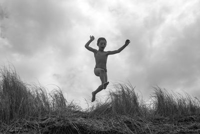 Low angle view of man jumping on field against sky