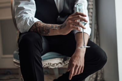 Midsection of groom holding champagne flute