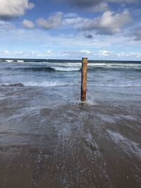 Wooden posts on beach against sky