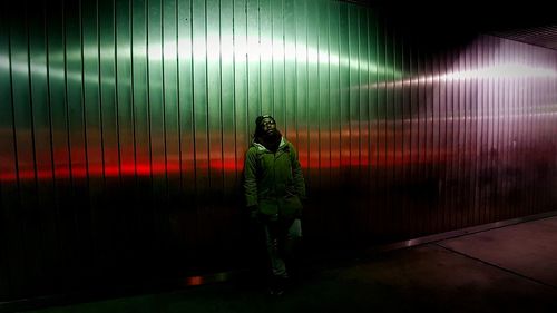 Full length of man standing against illuminated wall