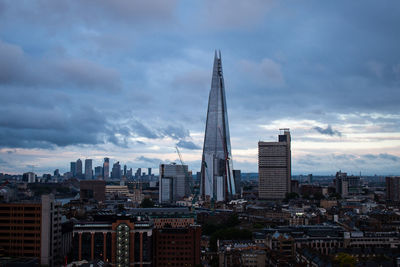 Modern buildings in city against cloudy sky