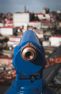 Close-up of coin-operated binoculars against buildings in city