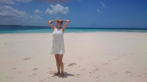 Full length of woman standing on sand at beach against sky