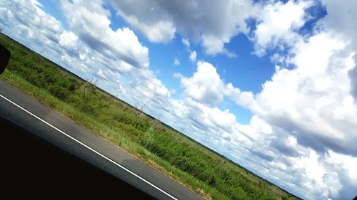 Road by field against sky