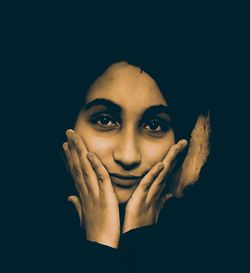 Portrait of young woman against black background